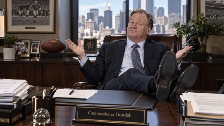 Roger Goodell sitting behind his desk with his feet up and shrugging in his office.