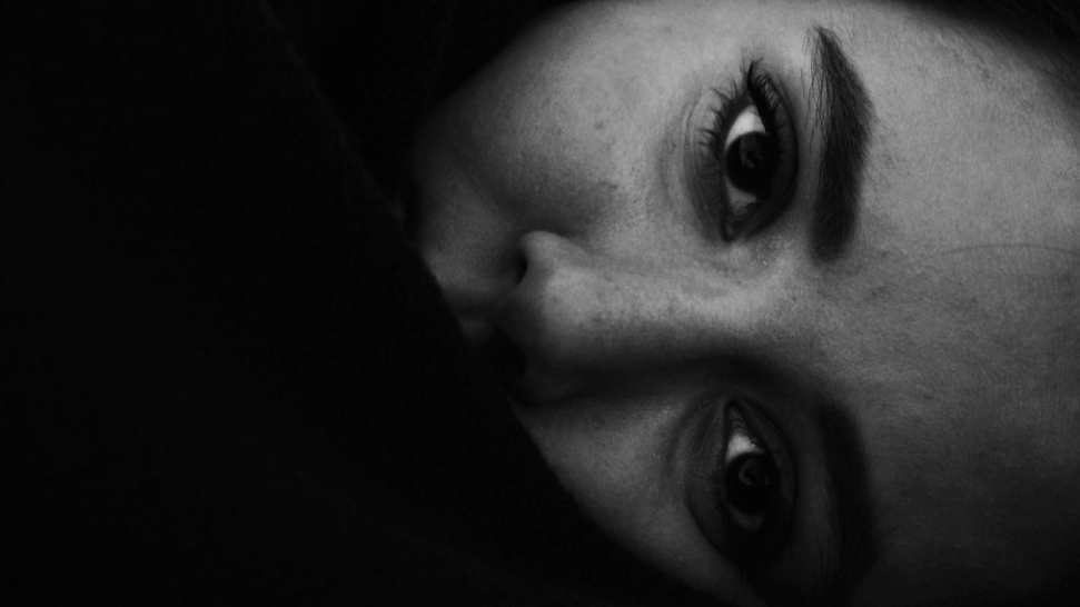A woman lies awake in bed at night, resting her head on a pillow.
