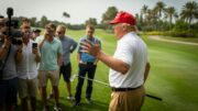 President Donald Trump speaks to reporters on a Florida golf course while holding a golf club, discussing the government shutdown and sending troops to New Orleans.