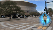 A man in futuristic clothing stands outside the Caesars Superdome in New Orleans holding a glowing sign that reads, “If you want civilization to survive, turn off the games,” surrounded by faint blue energy as cars pass by.
