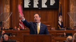 Louisiana lawmaker speaking at the senate podium holding a censored pink object during debate over a proposed Sx activity tax.